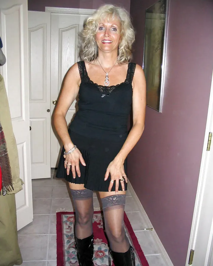 Femme en haut gris ajusté, buste visible, collier fin, photo floue en lumière vive.