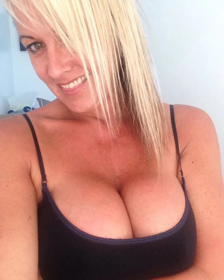 Femme aux cheveux blancs, portant un haut noir, souriant vers l'appareil photo.