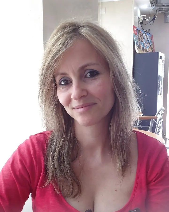 Femme en t-shirt rouge, regardant la caméra, sourire discret