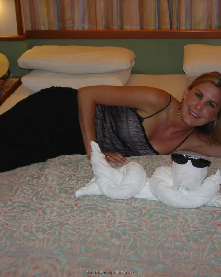 Femme aux cheveux blonds mi-longs portant un haut noir, assise, regardant l'appareil photo avec un sourire discret.