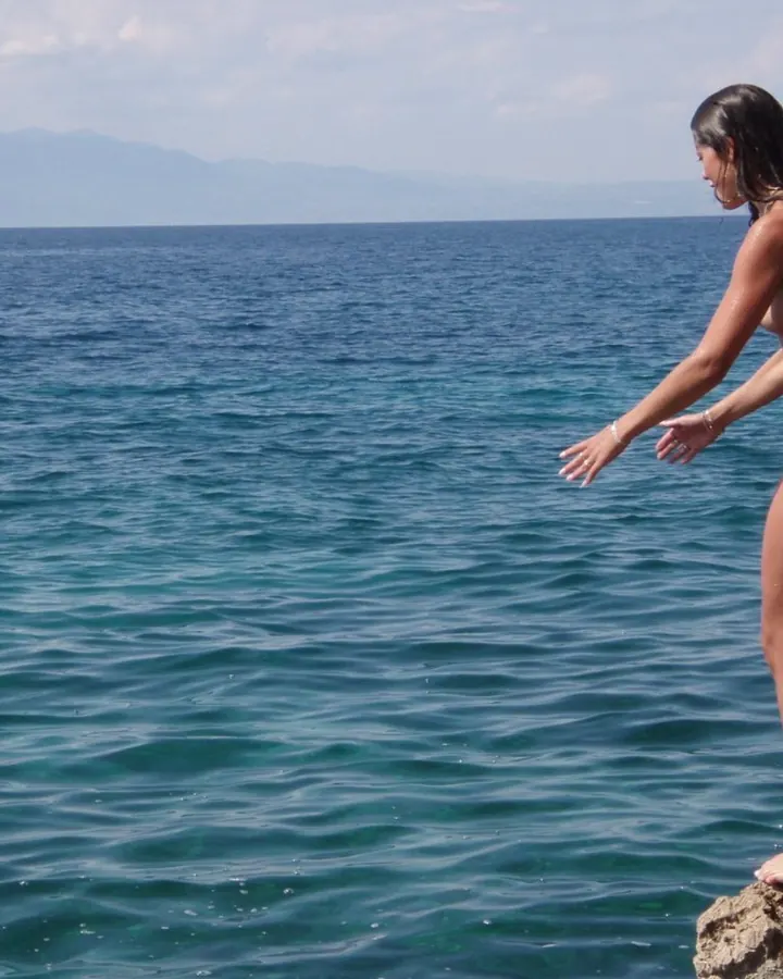 Femme en tenue noire, allongée sur le sol, les jambes étendues, devant une grande fenêtre.