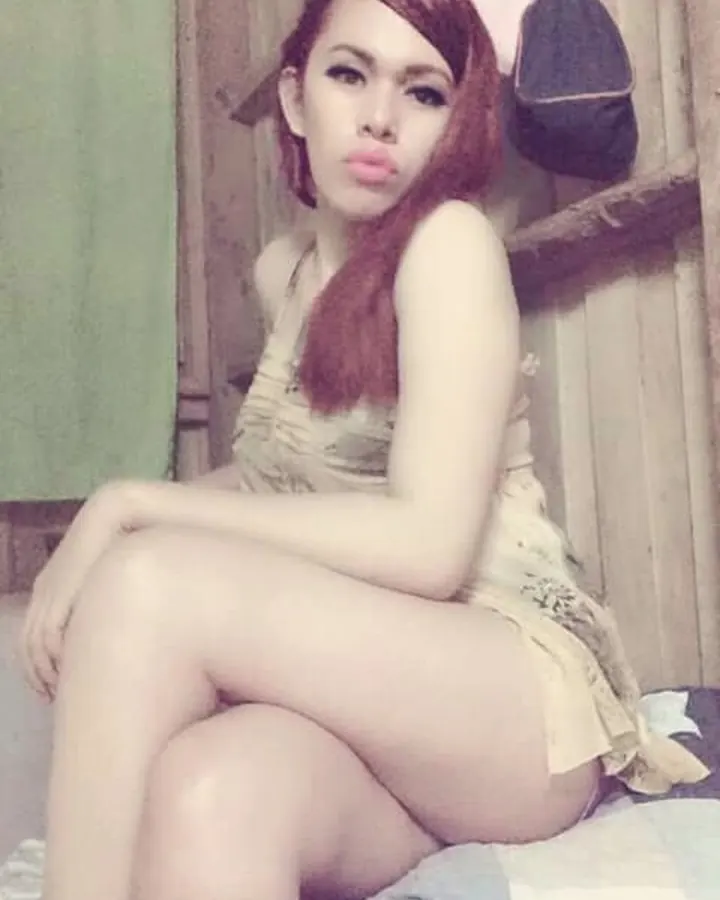 Femme latine en robe jaune, allongée sur un lit, jambes croisées, chaussures dorées.