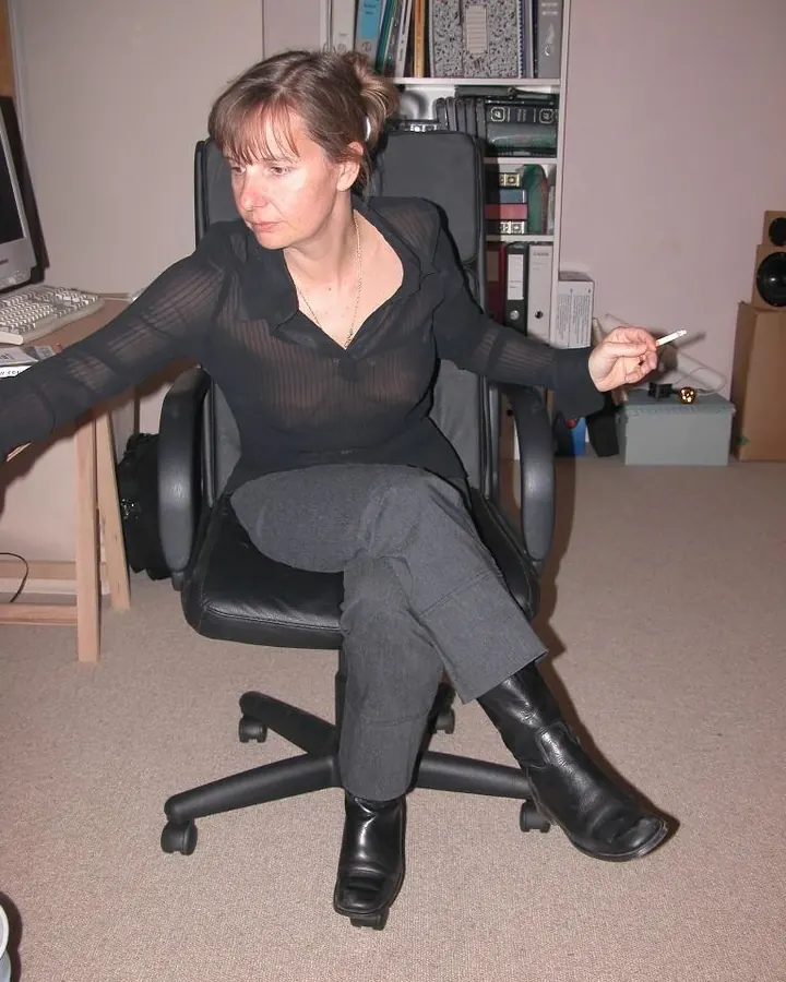 femme brune en blouse noire, cigarette, chaise de bureau