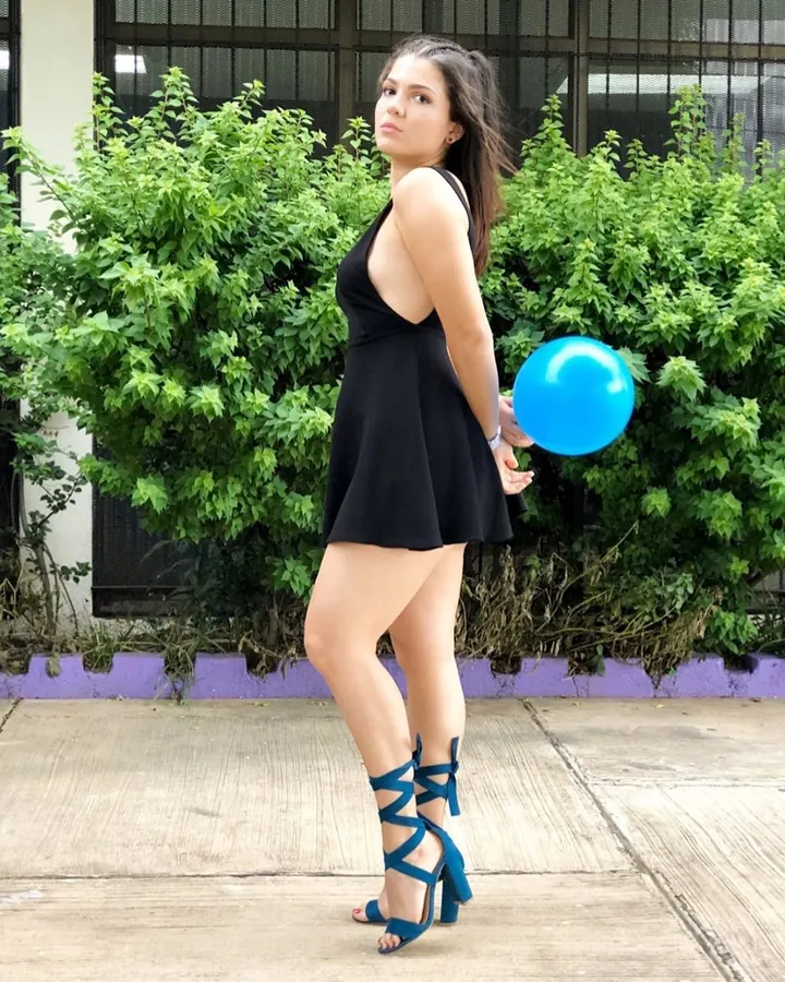 femme brune en robe noire dos nu, ballon bleu