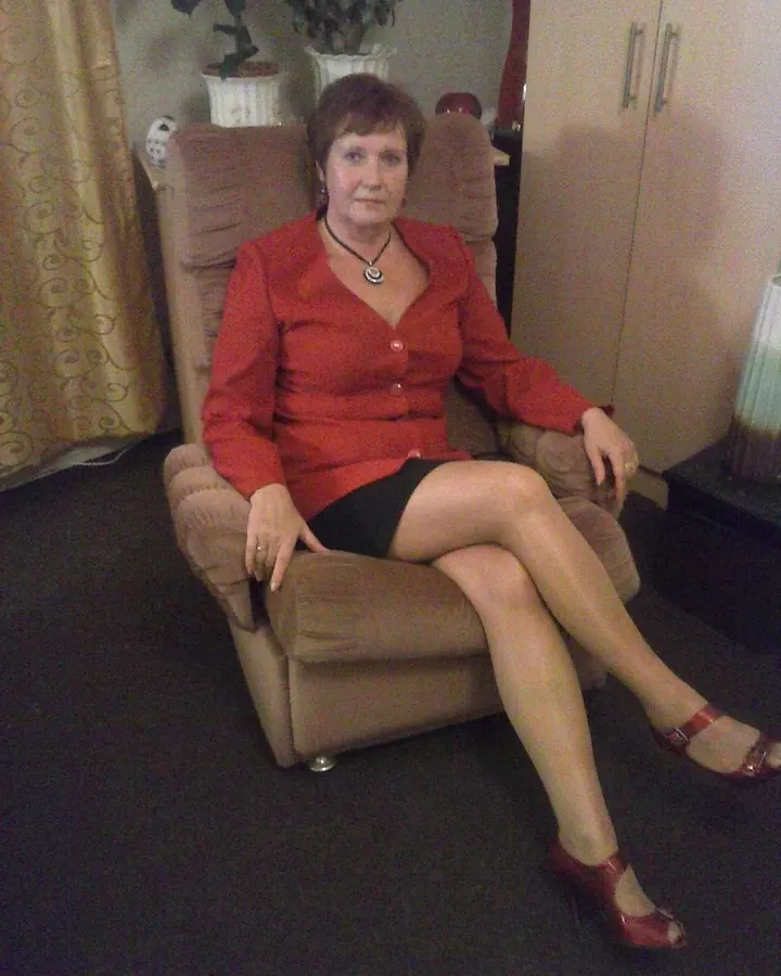 Femme en tenue noire, posant dans un intérieur avec un miroir.