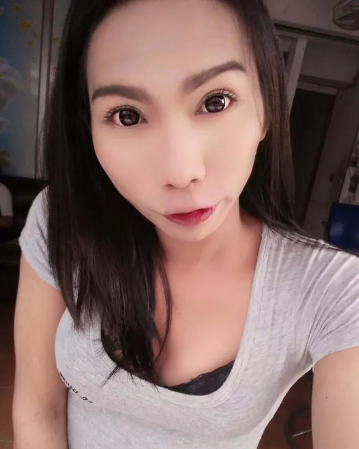 Femme asiatique en t-shirt gris, regardant l'objectif en selfie.