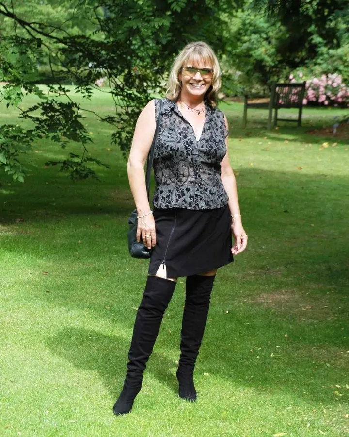 Femme aux cheveux blonds platine, souriante, en tenue décontractée, posant dans un jardin.