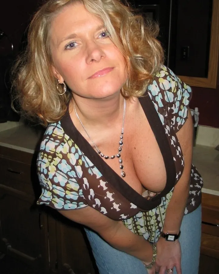 Femme aux cheveux blonds, regard bleu, en tenue décontractée, posant dans un cadre intérieur.