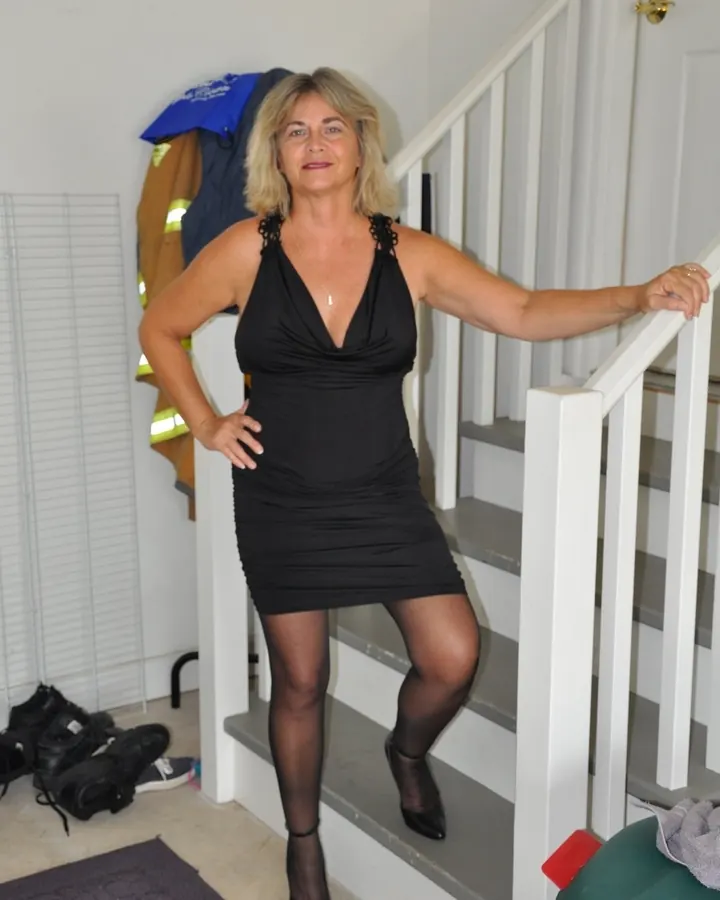 Femme aux cheveux blonds, en tenue décontractée, posant dans un cadre intérieur.