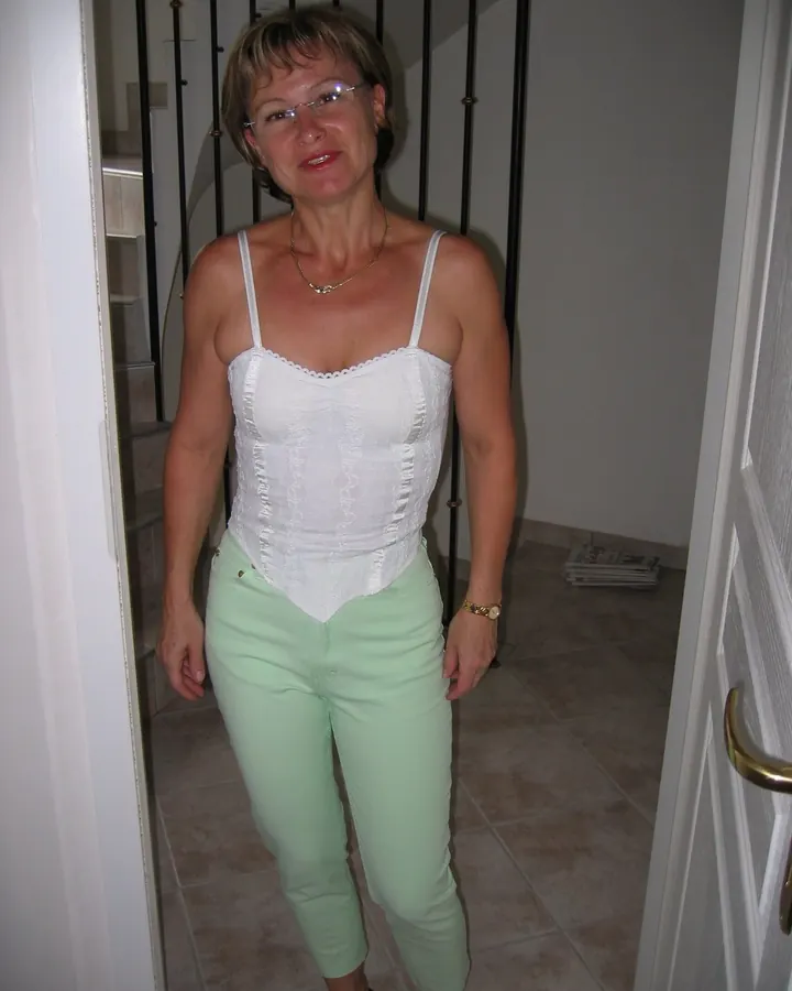 Femme aux cheveux châtains, en tenue décontractée, posant dans un cadre intérieur.