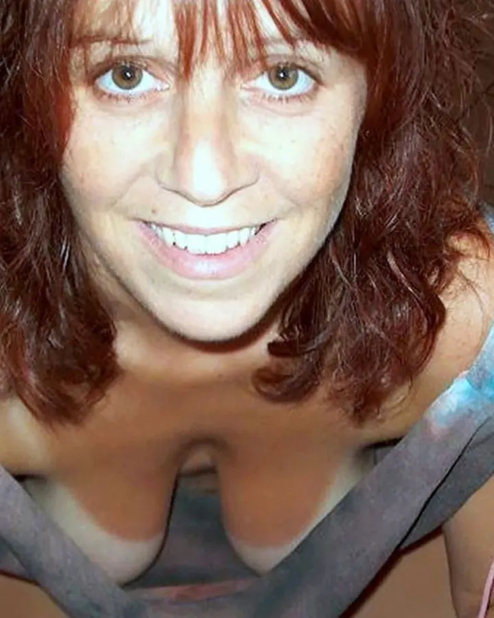 Femme nue torse, cheveux bruns, se tenant près d'une fenêtre, regardant directement l'appareil.