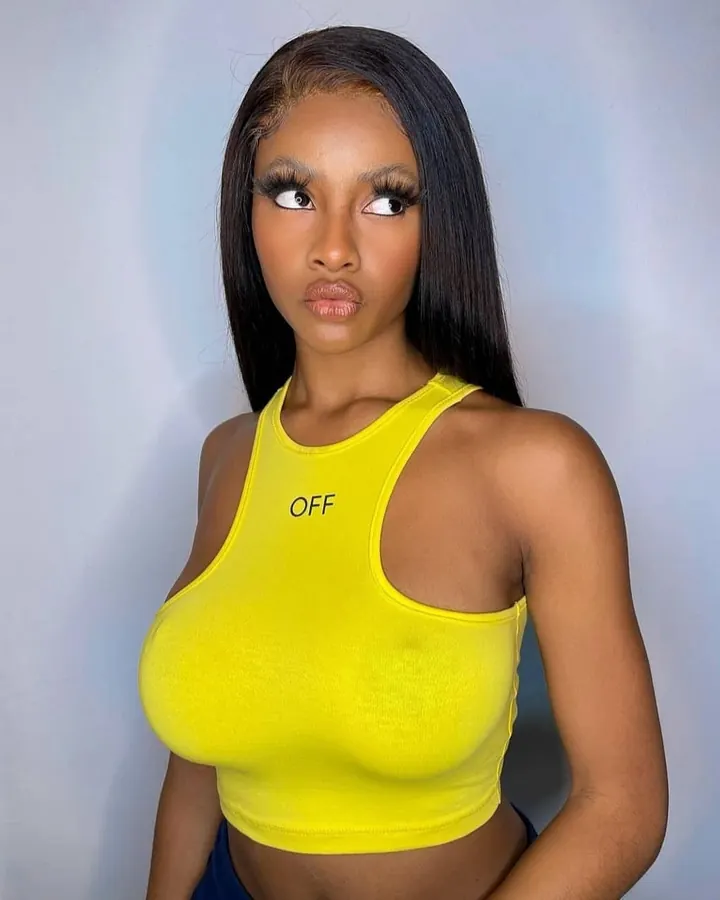 Femme aux cheveux noirs et peau mate, portant un haut jaune fluo avec l'inscription 'OFF', regardant vers le côté avec un regard perçant.