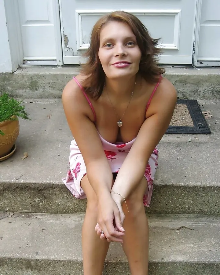 Femme aux cheveux châtains portant un haut rose, assise sur des marches en extérieur